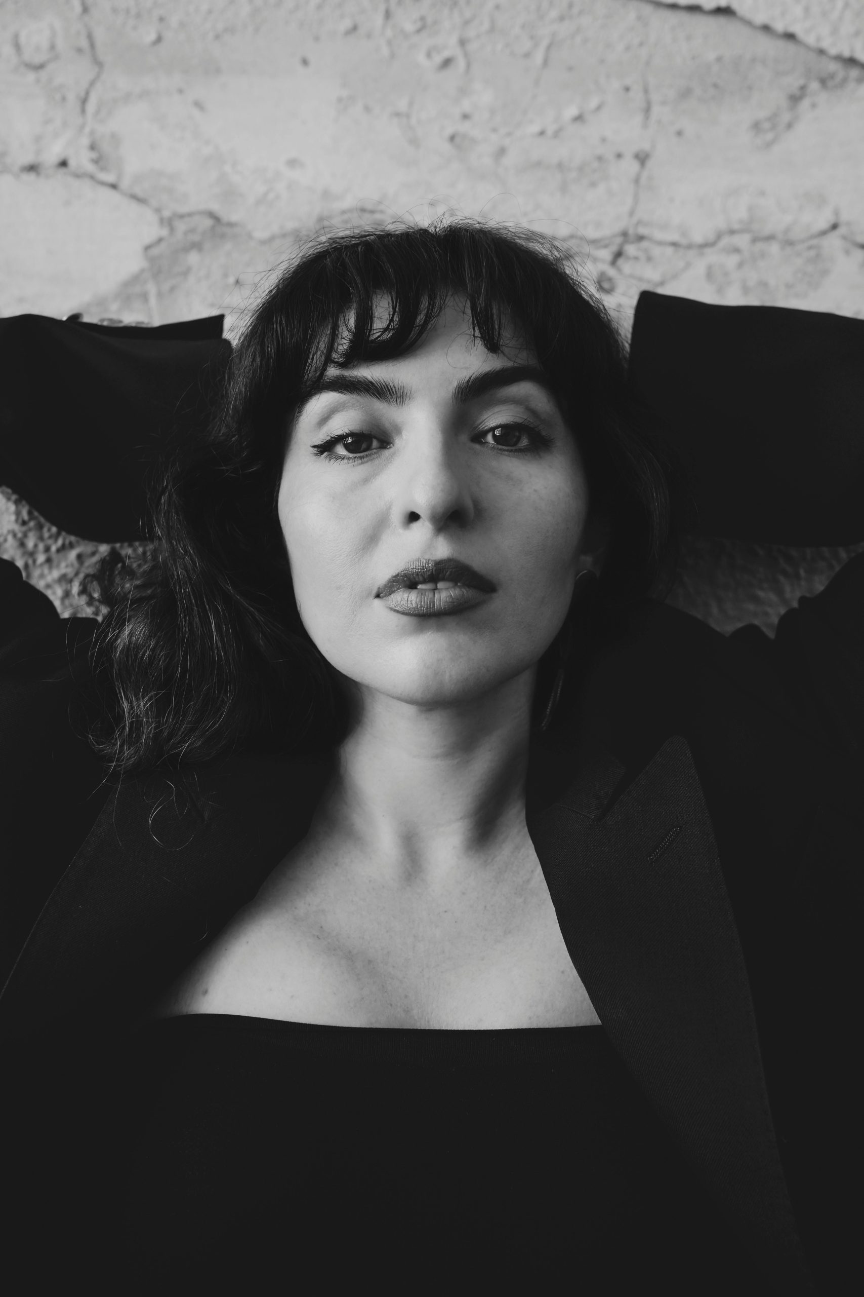 Black and white portrait of a woman with long hair, lying down in a casual pose.